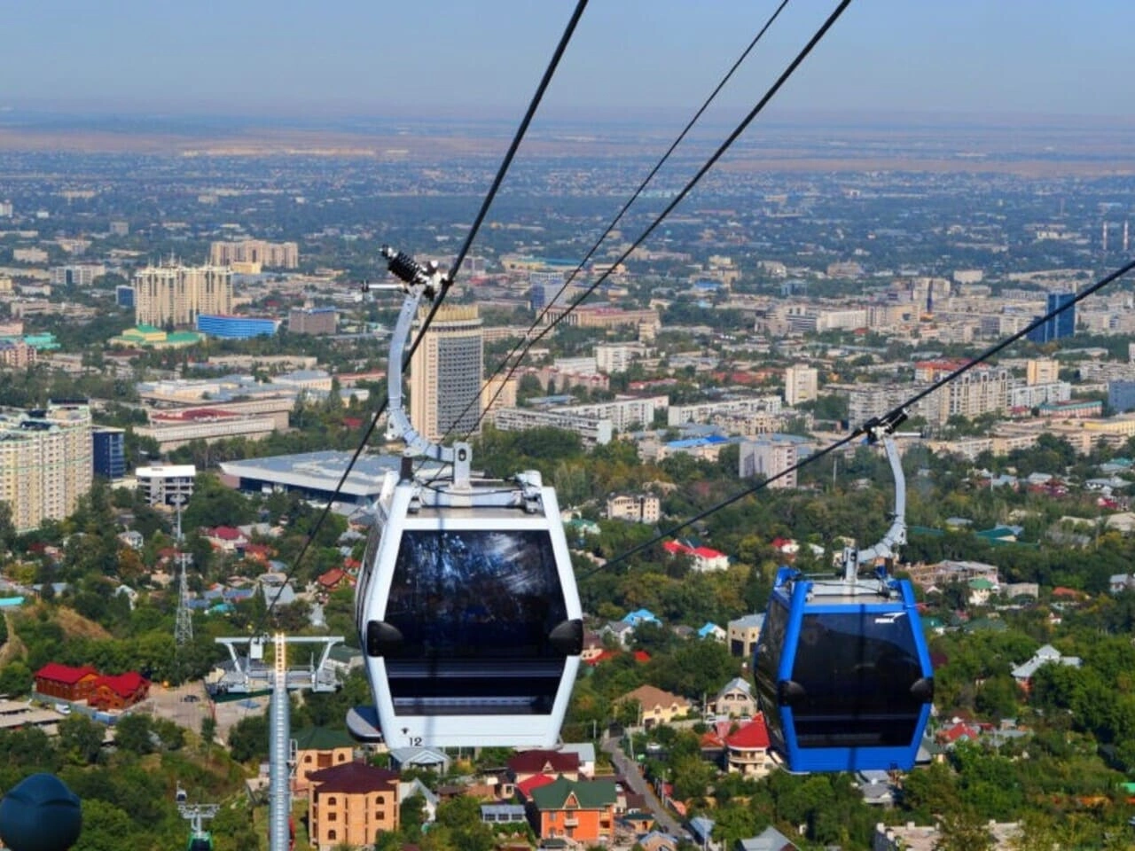 Cable cars travelling above Almaty towards Kok Tobe Hill with a panoramic city view
