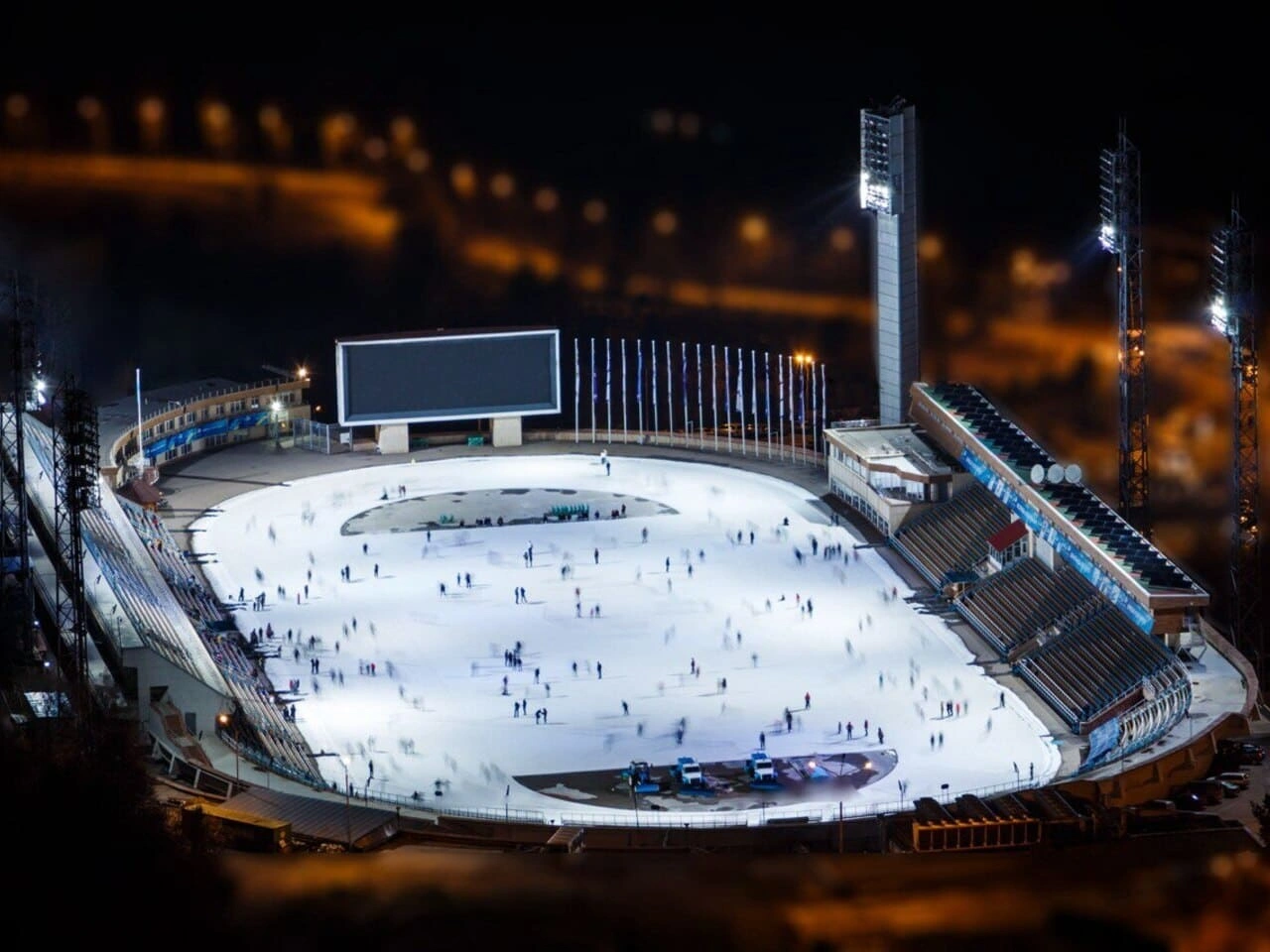 Night aerial view of the Medeo ice rink in Almaty with skaters on the illuminated ice